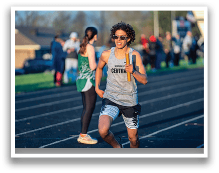 A man running on a track with a woman behind him. Description generated by AI