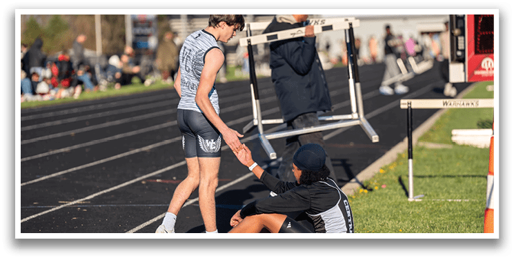 A man is bending over another man who is kneeling on the ground. Description generated by AI