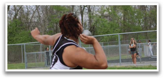 A man in a black and white track suit is running on a track. Description generated by AI