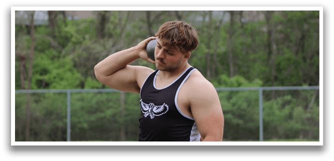 A man wearing a black and white shirt and black shorts is standing on a field. Description generated by AI