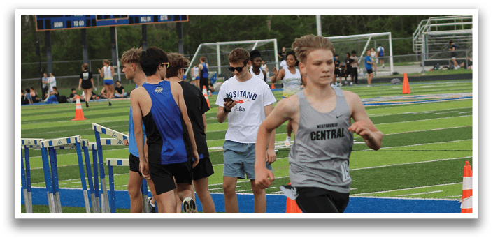 A man running on a track with a blue and orange cone in front of him. Description generated by AI