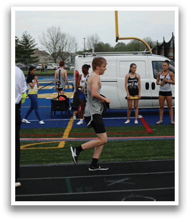 A man running on a track with a white van in the background. Description generated by AI