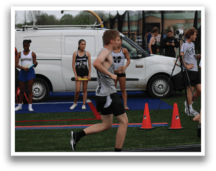 A man running on a track with orange cones. Description generated by AI