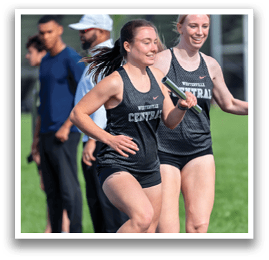 Two women running on a track. Description generated by AI