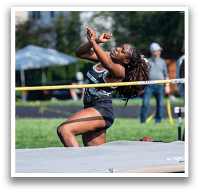 A woman is jumping in the air on a track. Description generated by AI