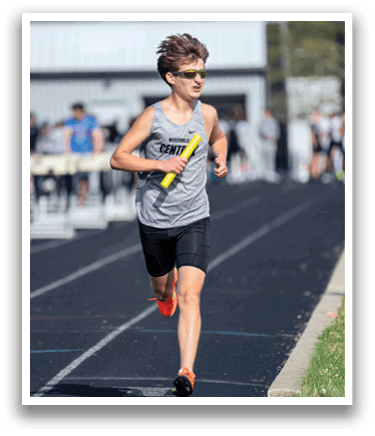 A man running on a track with a yellow frisbee. Description generated by AI