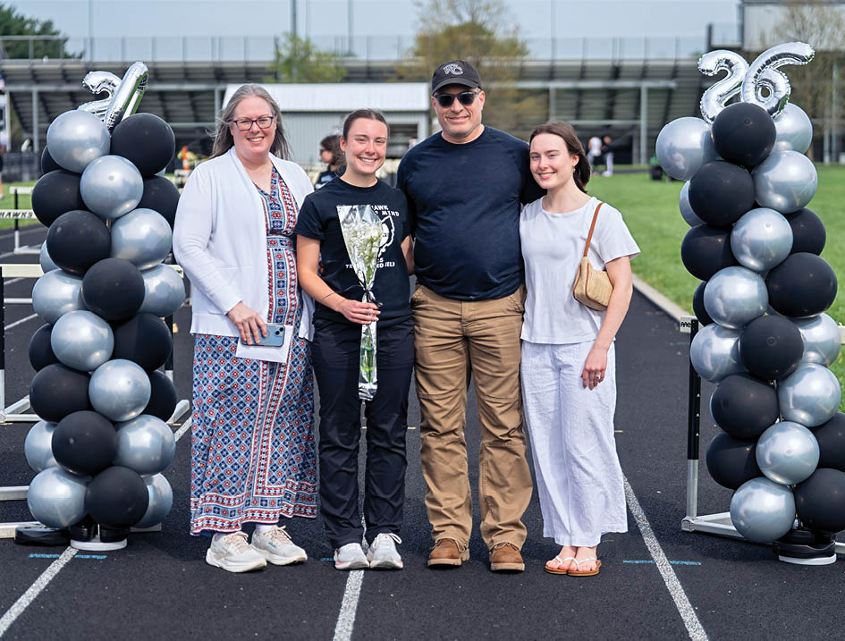 A group of people standing in front of a black and silver arch. Description generated by AI