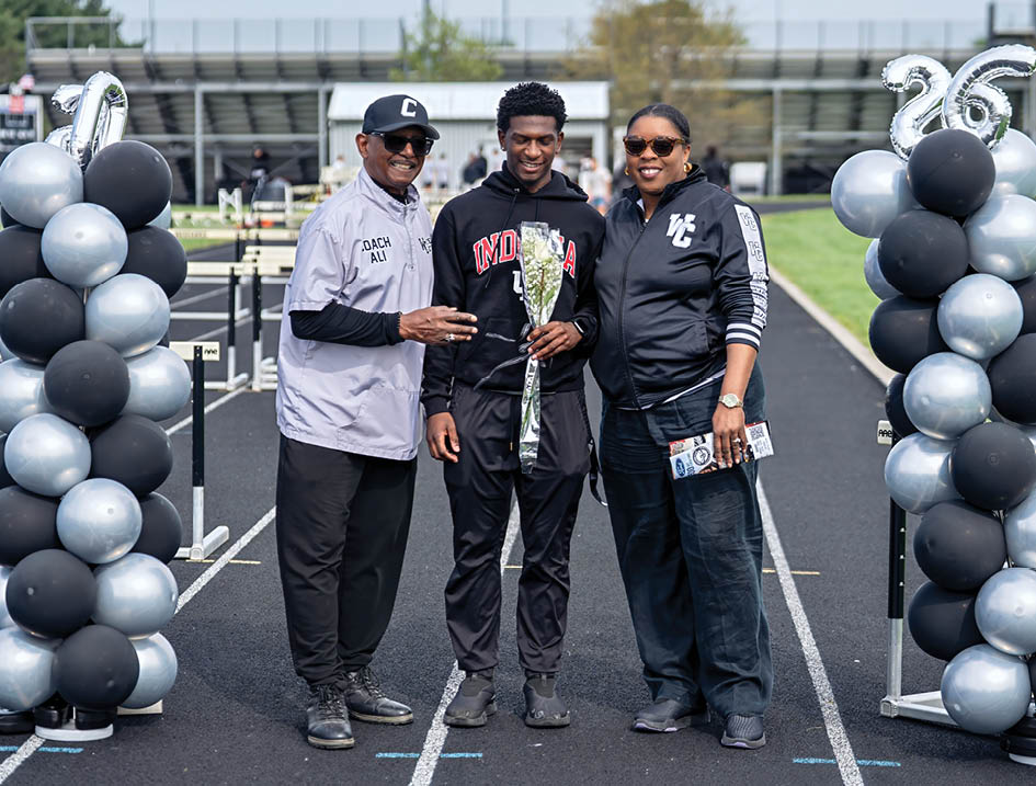 Three people standing on a track with a trophy. Description generated by AI