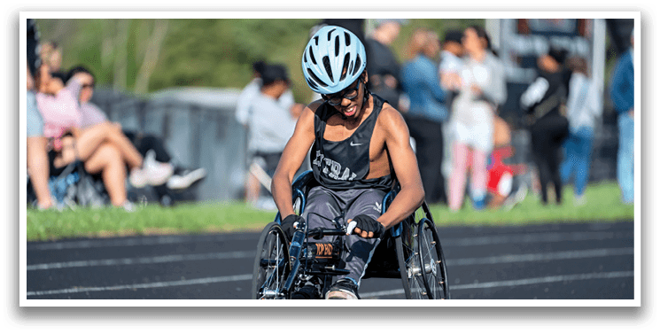 A boy in a wheelchair is racing on a track. Description generated by AI