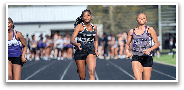 Three girls running on a track. Description generated by AI