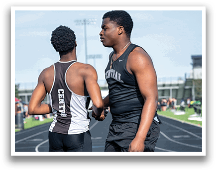 Two men wearing black and white shirts and shorts are standing on a track. Description generated by AI