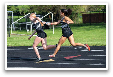 Two girls running on a track. Description generated by AI