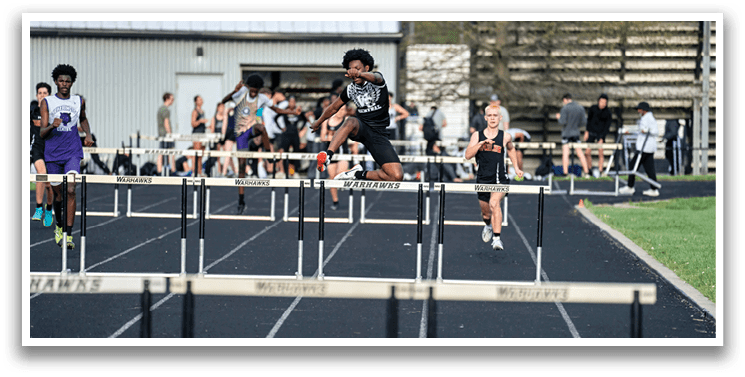 A black and white photo of a track athlete jumping over a hurdle. Description generated by AI