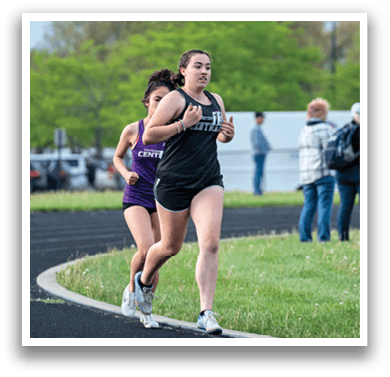 Two girls running on a track. Description generated by AI