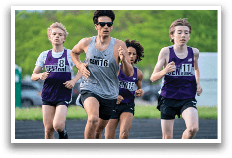 Three boys running on a track. Description generated by AI