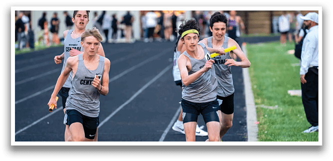A boy running on a track with a yellow frisbee in his hand. Description generated by AI