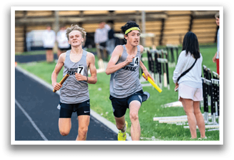 Two boys running on a track. Description generated by AI