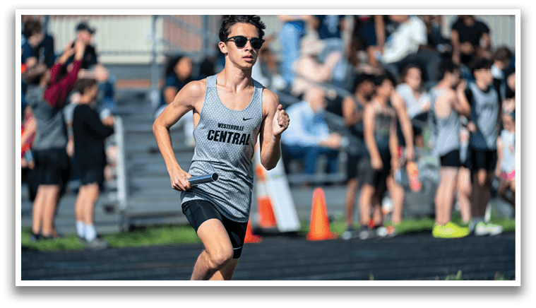 A runner in a grey and black shirt is running on a track. Description generated by AI