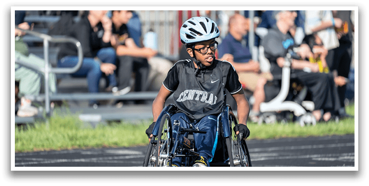 A boy in a wheelchair is racing. Description generated by AI
