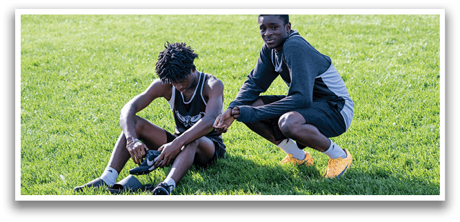 Two boys sitting on grass. Description generated by AI