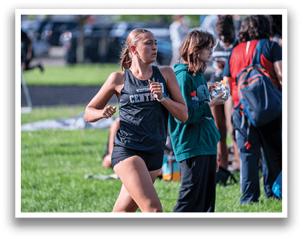 A woman running in a black and grey shirt. Description generated by AI