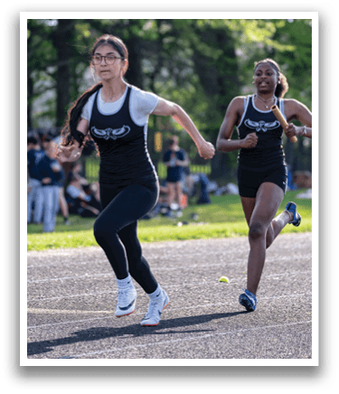 Two girls running on a track. Description generated by AI