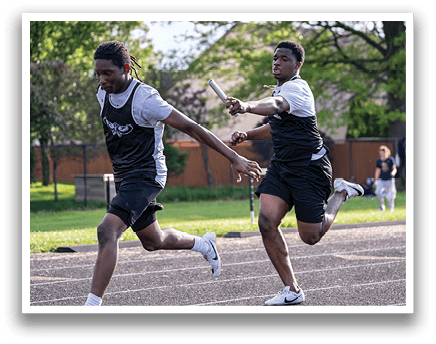 Two young men running on a track. Description generated by AI