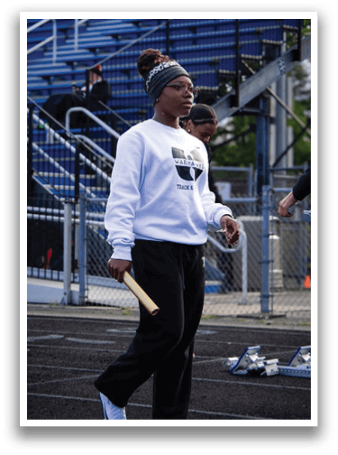 A woman wearing a white sweatshirt and black pants holding a yellow baton. Description generated by AI