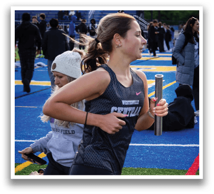 A woman wearing a black and gray shirt is running on a field. Description generated by AI