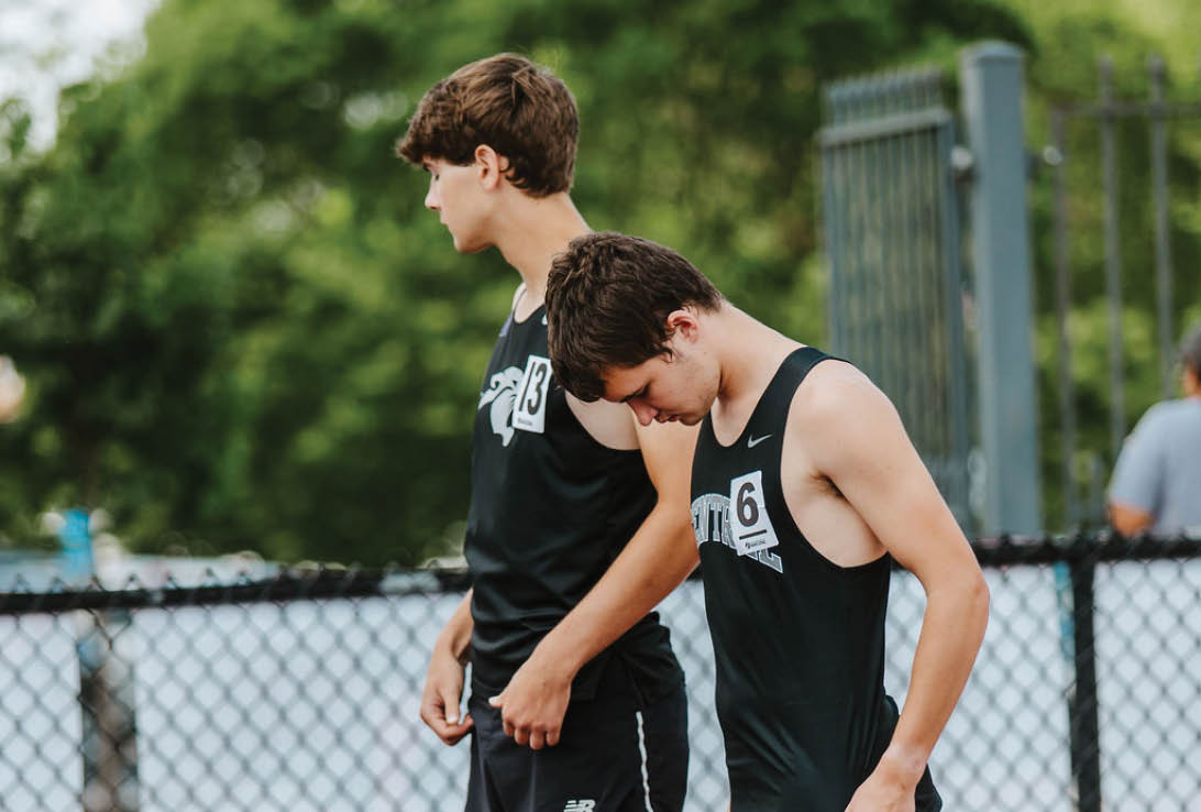 Two men standing on a track. Description generated by AI