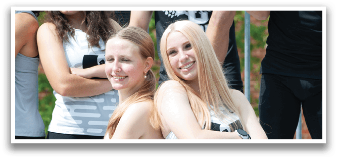 Two girls standing on a staircase. Description generated by AI