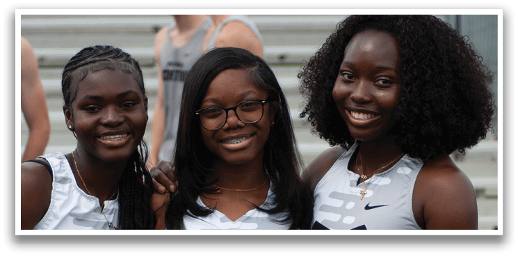 Three women wearing grey and black uniforms. Description generated by AI