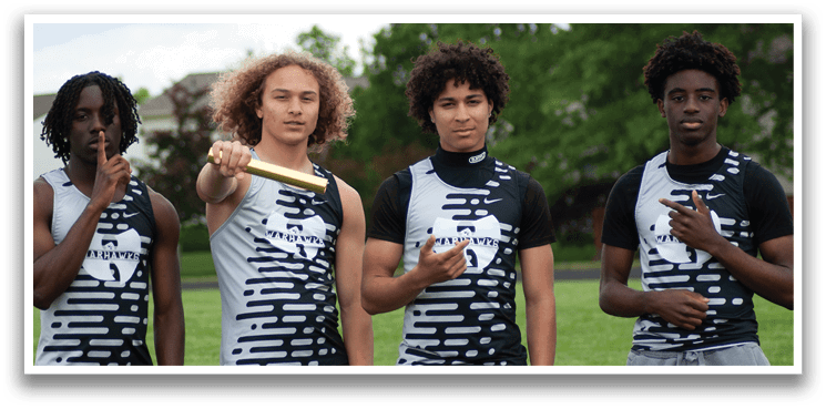 Four young men standing in a field, wearing black and white shirts. Description generated by AI