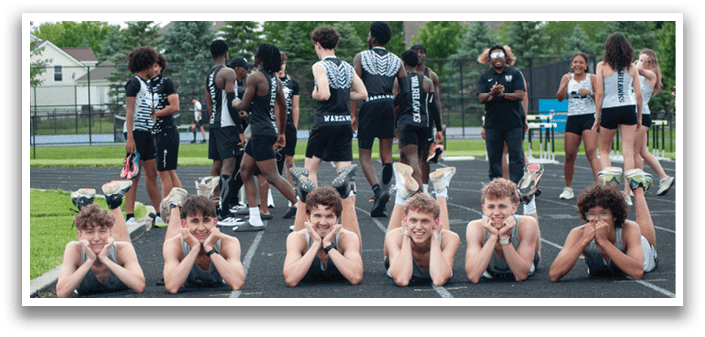 A group of young men laying on the ground on a track. Description generated by AI