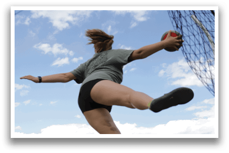 A woman is jumping in the air with a red ball in her hand. Description generated by AI