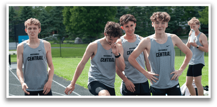 A group of young men wearing gray and black shirts and shorts are standing on a track. Description generated by AI