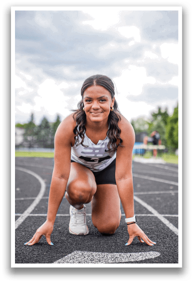 A woman is crouching on a track. Description generated by AI