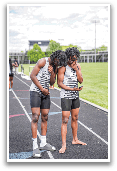 Two men standing on a track. Description generated by AI