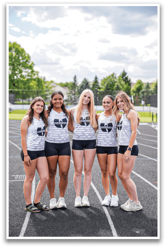 Five girls standing on a track. Description generated by AI