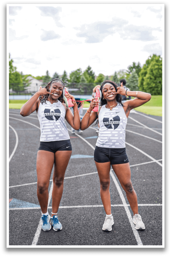 Two women standing on a track. Description generated by AI