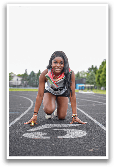A woman is kneeling on a track with a number 5 on the ground in front of her. Description generated by AI