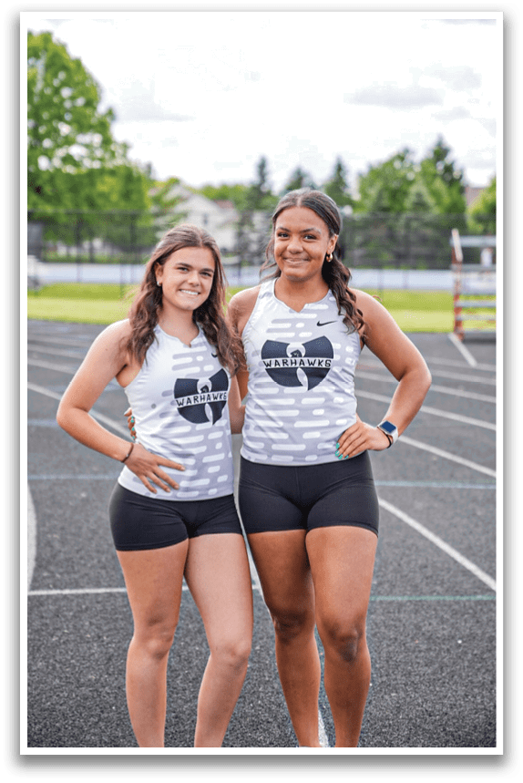 Two girls standing on a track. Description generated by AI