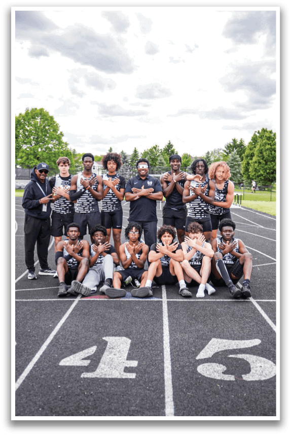 A group of people posing for a picture on a track. Description generated by AI