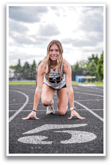 A woman is kneeling on a track. Description generated by AI