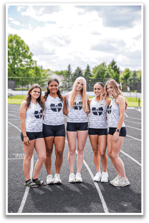 Five girls standing on a track. Description generated by AI