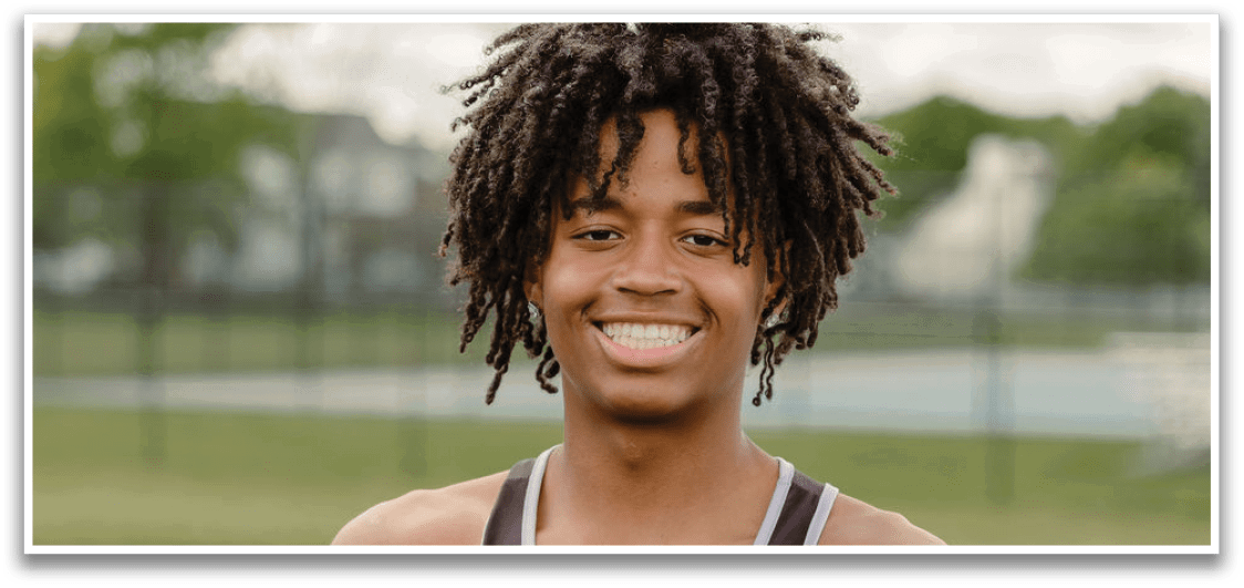 A young man with dreadlocks and a black tank top is posing for a picture. Description generated by AI