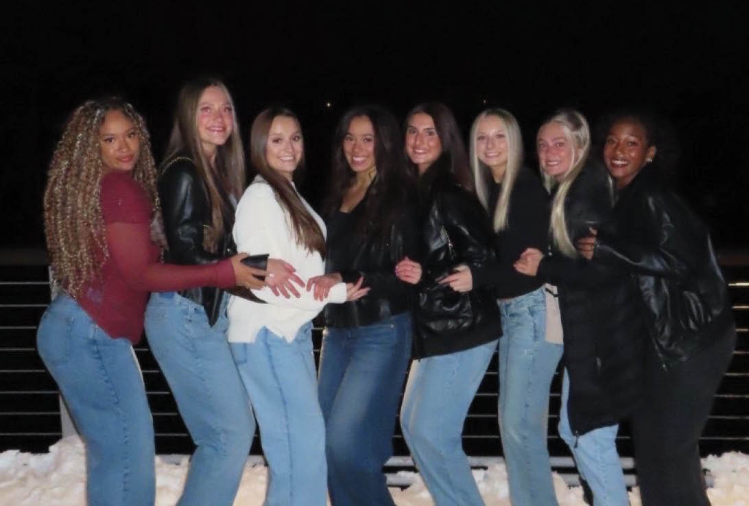 A group of women standing on a sidewalk. Description generated by AI