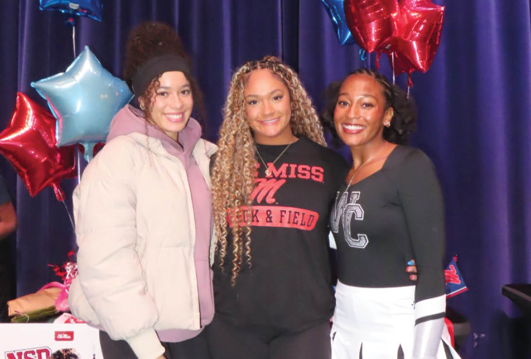 Three women standing in front of a blue curtain. Description generated by AI