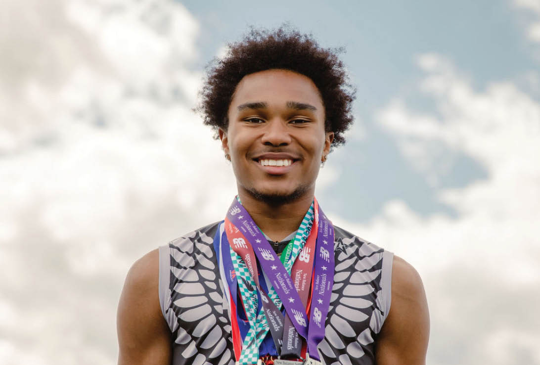 A man wearing a black shirt with gold medals around his neck. Description generated by AI