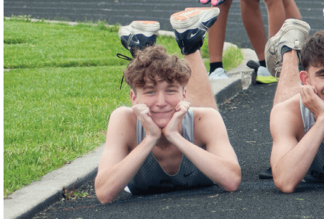A group of young men are laying on the ground on a track. Description generated by AI